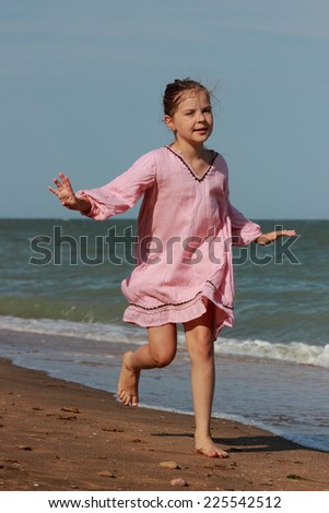 Beautiful little girl wearing summer dress playing and running over the seaside in Crimea