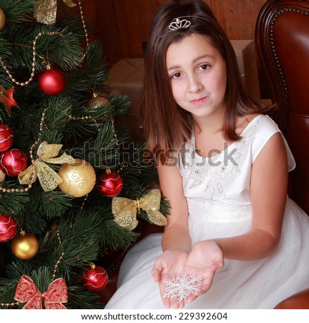 Happy little girl over christmas tree on Holiday theme/Pretty smiley princess in white dress