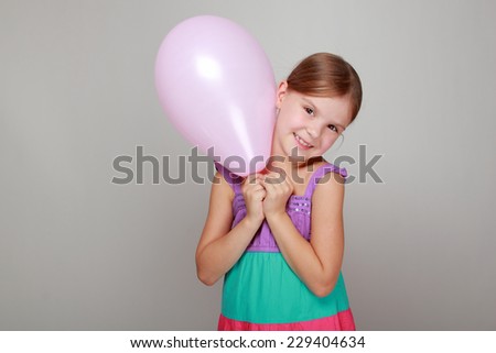 Beautiful little girl with a sweet smile holding a pink air balloon on Holiday