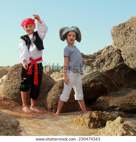 Caucasian boy and girl pirate corsair pirate holding the map in search of treasure on the beach
