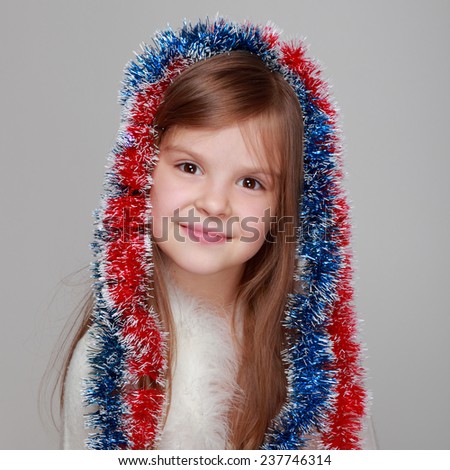 Joyful cute kid with a sweet smile holding a Christmas and New Year decorations on gray background