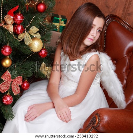 Lovely portrait of little Angel with Christmas gifts over Christmas tree full of beautiful decoration on Holiday theme/Lovely angel with white wings on Holiday theme