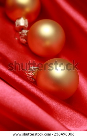 Small glass golden balls over red background on Christmas/Cute golden decoration over satin texture on Holiday theme