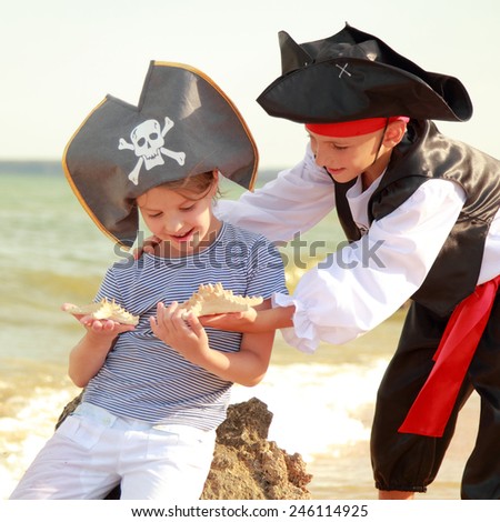 Beautiful little boy and girl dressed in pirate costumes and holding starfish on the beach