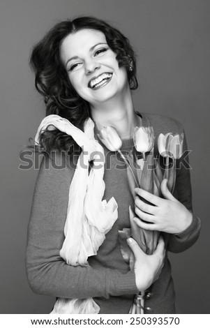 Black and white image of beautiful young woman with fresh tender tulips