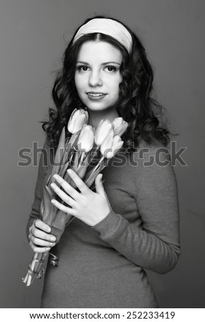 Studio black and white image of beautiful young woman with fresh tender tulips