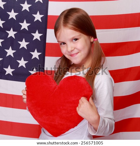 beautiful cheerful little girl with a sweet smile, holding a big red heart