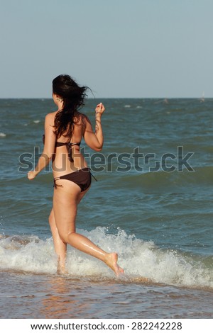 Sexy young Caucasian female model in bikini posing on beach over the Black Sea, Crimea,Russia