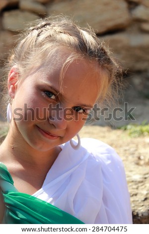 Pretty smiling young girl in a vintage tunic as a Greek goddess on a background of the archaeological site of the ancient city in the village Geroevskoe, Republic of Crimea