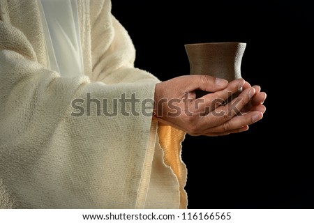 Jesus hands holding cup over dark background