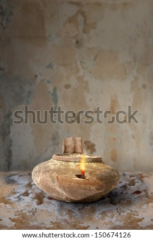 Ancient Middle Eastern oil lamp on clay surface