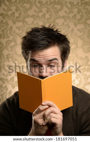 Portrait of young man showing surprise while reading over retro background