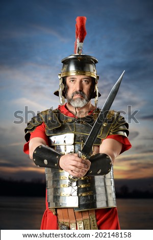 Portrait of Roman centurion with sword over sunset background