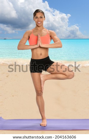 African American woman practicing yoga on the sand of exotic beach
