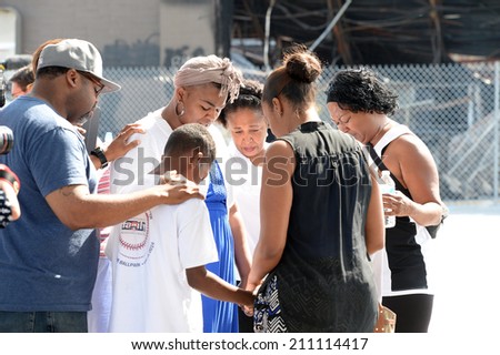 FERGUSON, MO/USA -  AUGUST 15, 2014: Group prays at the site of destroyed Quick Trip after Police Chief Thomas Jackson release of the name of the officer that shot Michael Brown.