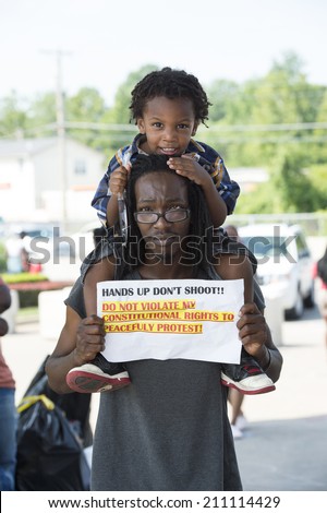 FERGUSON, MO/USA -  AUGUST 15, 2014: Man and child hold sign at the site of destroyed Quick Trip after Police Chief Thomas Jackson release of the name of the officer that shot Michael Brown.