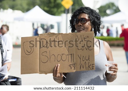 FERGUSON, MO/USA -  AUGUST 15, 2014: Woman holds sign at the site of destroyed Quick Trip after Police Chief Thomas Jackson release of the name of the officer that shot Michael Brown.