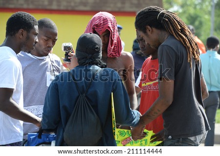 FERGUSON, MO/USA -  AUGUST 15, 2014: Men pray at the site of burnt Quick Trip after Police Chief Thomas Jackson release of the name of the officer that shot Michael Brown.