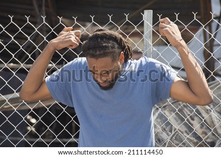 FERGUSON, MO/USA -  AUGUST 15, 2014: Man holds on to fence at the site of destroyed Quick Trip after Police Chief Thomas Jackson release of the name of the officer that shot Michael Brown.