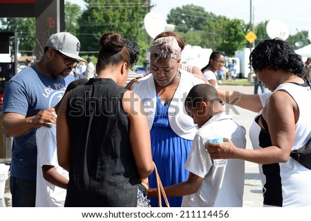 FERGUSON, MO/USA- AUGUST 15, 2014: Group prays at the site of destroyed Quick Trip after Police Chief Thomas Jackson release of the name of the officer that shot Michael Brown.
