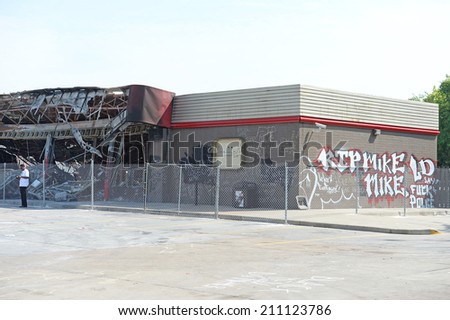 FERGUSON, MO/USA  AUGUST 15, 2014: Demonstrator stands in front of destroyed Quick Trip after Police Chief Thomas Jackson release of the name of the officer that shot Michael Brown.