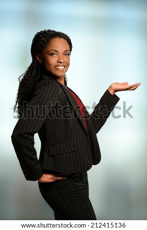 Portrait of African American businesswoman presenting with palm up inside office building