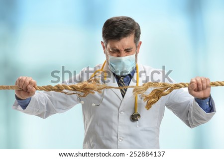 Doctor holding frayed rope inside hospital building