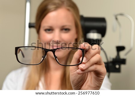 Female eye doctor holding glasses - focus on glasses