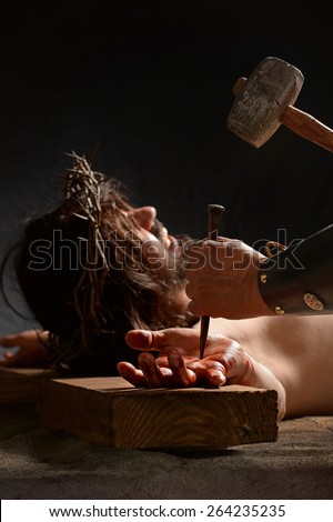 Jesus hand being nailed to the cross by Roman soldier