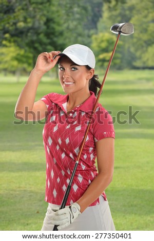 Portrait of beautiful young golfer tipping cap on golf course
