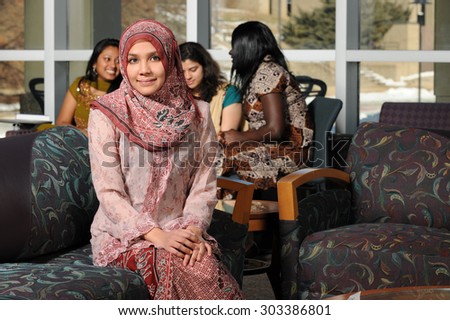 Portrait of young Muslim woman with headscarf inside college building on campus