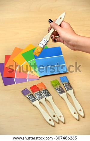 Paintbrushes and swatches with hand holding brush with yellow paint
