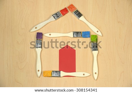 House made out of paintbrushes with different colors and door from color sample