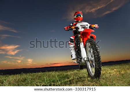 Man riding motocross motorcycle at sunset - With copy space