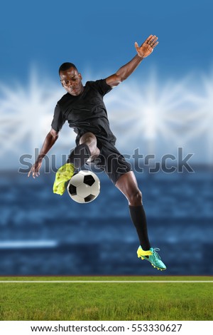 African American soccer player kicking ball inside stadium