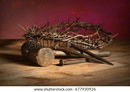 Crown of thorns, mallet and nails over vintage table over red background