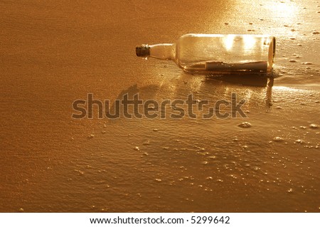 Message in a bottle on a sandy shore at sunset
