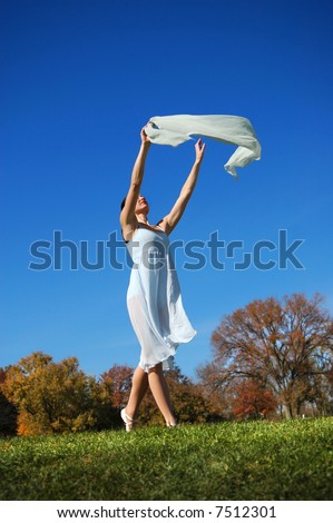 Ballerina in light outfit dancing outdoors in a fall day.