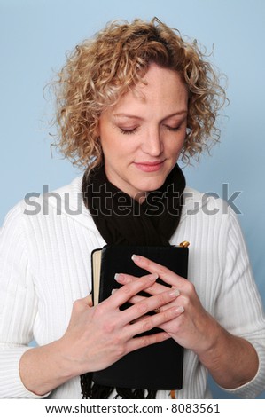 Woman with Bible praying with eyes closed