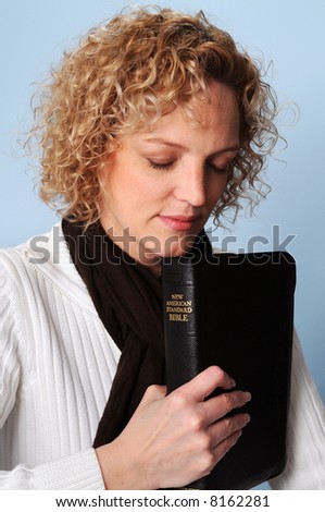 Young woman praying holding a Bible