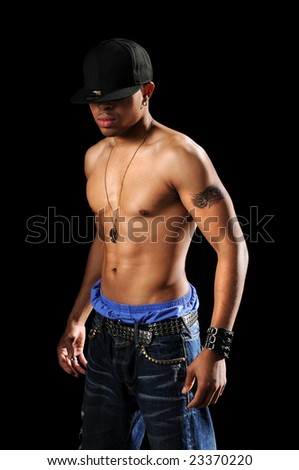 stock photo Hip Hop man with tattoos barechested standing over a black 