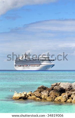 Cruise ship anchored in tropical waters with rocks in foreground