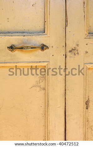 Old grunge yellow door with bronze handle