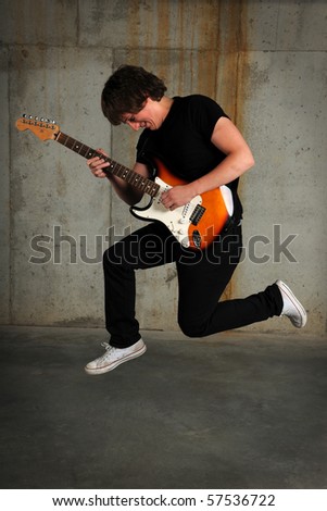 Young guitar player jumping over grunge background