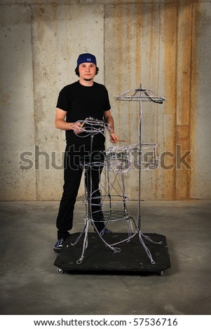 Young drummer playing on make-believe drummer set made of wires over grunge background