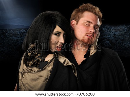 Vampire woman biting man on the neck