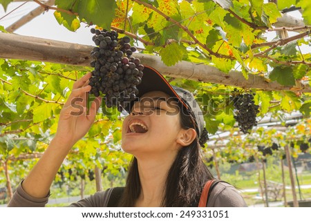 Asian Thai young woman eating grapes in a vineyard