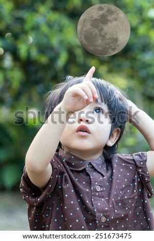 Portrait of asian cute little boy pointing upwards the moon