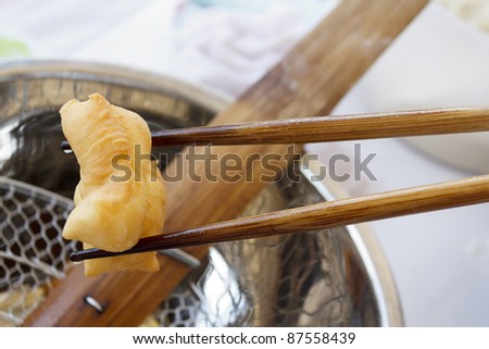 Bamboo chopsticks holding deep-fried dough stick, Chinese dough nut, breakfast or snack of the chinese people