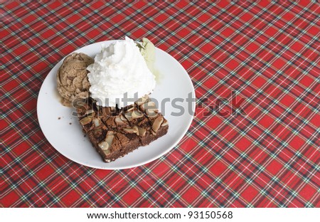 Piece of chocolate brownie with chocolate ice cream and green tea ice cream and whipped cream on plate
